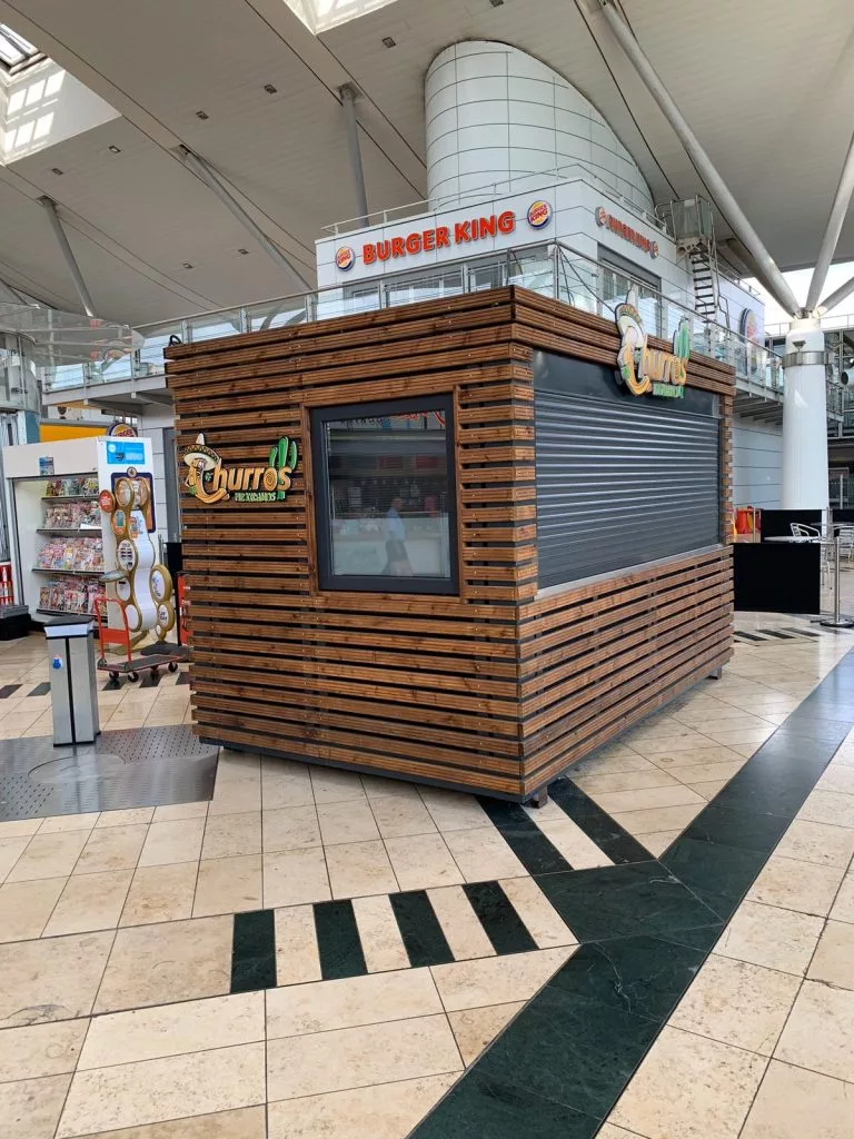 Chioșc comercial din container placat cu lemn, cu fereastră de servire, într-un mall